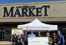Group holding a Central California Food Bank donation check in front of The Market in Fresno