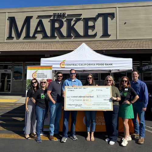 KMJ Feeding Families Fund Drive check presentation at The Market Group holding a Central California Food Bank donation check in front of The Market in Fresno