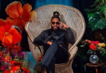 Raheem DeVaughn seated in a wicker chair surrounded by flowers and plants